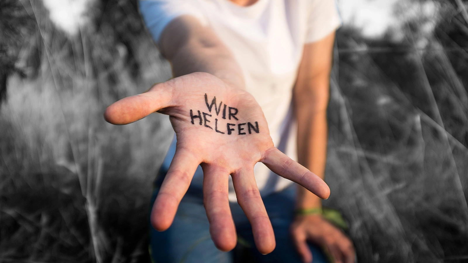 Eine ausgestreckte Hand, auf der Steht "Wir helfen"