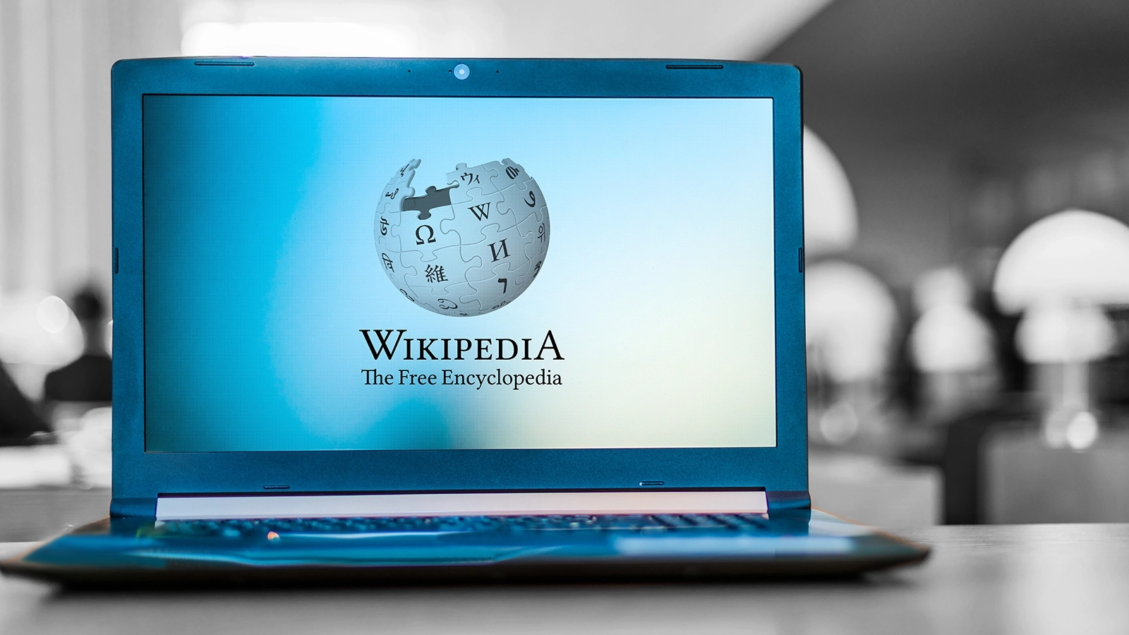 Ein Laptop steht auf dem Tisch, im Display sieht man das Wikipedia-Logo