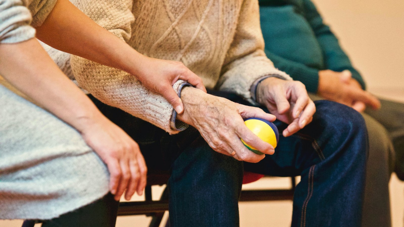 ein Mensch berührt die Hand einer älteren Person